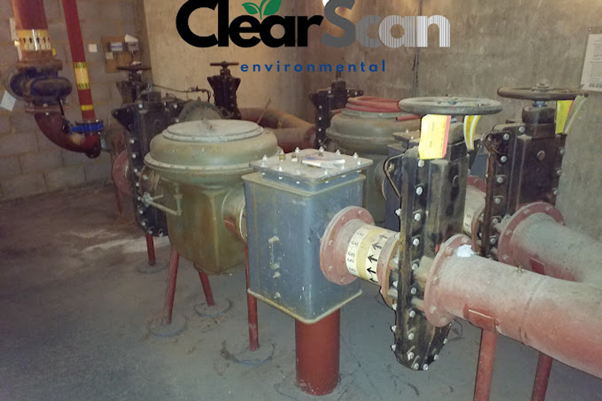 School estate building interior showing aged mechanical equipment and services requiring asbestos management survey