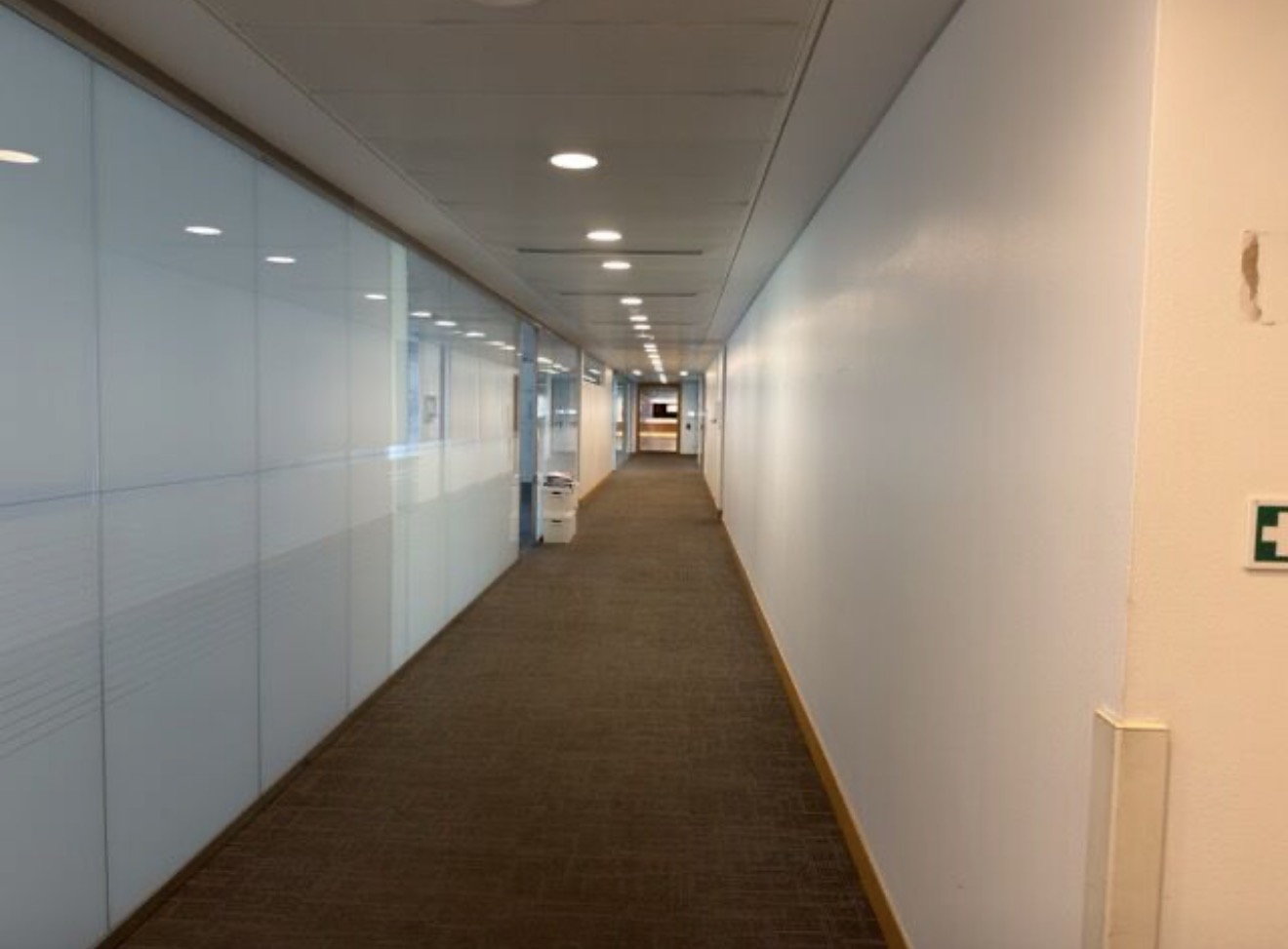 Office corridor inside One Silk Street with frosted glass partitions, carpet and a suspended ceiling with downlights